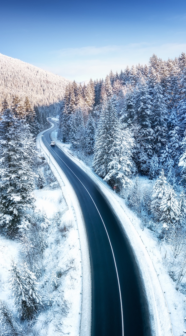 Aerial view on the road and forest at the winter time. Natural winter landscape from air. Forest under snow a the winter time. Landscape from drone