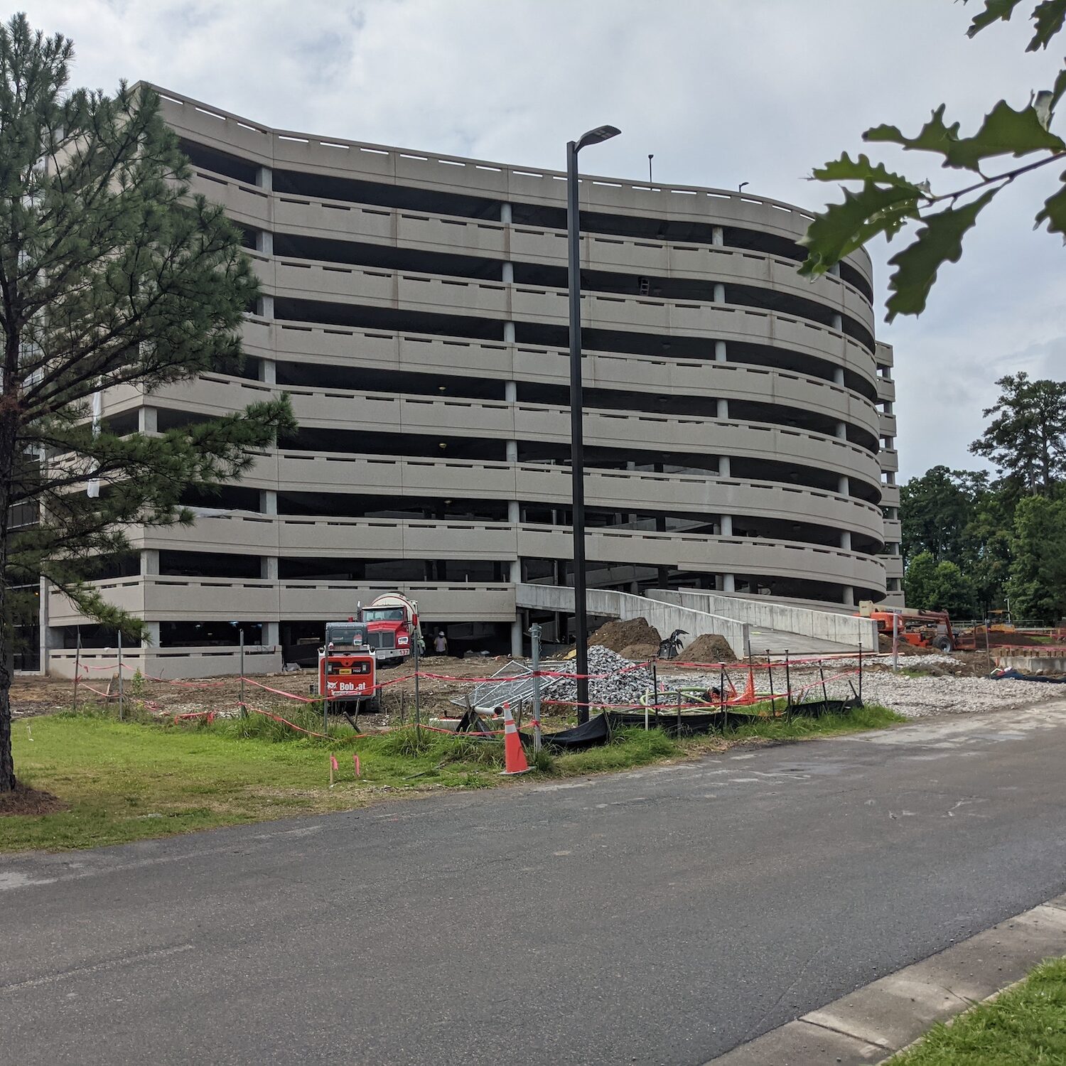 Ongoing construction of a modern multi-level parking garage, showcasing strong structural design and steady project progress, with vehicles and equipment active on-site.